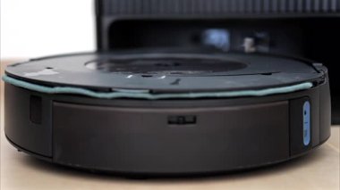Yerde hareket eden ve dönen siyah bir robot elektrikli süpürgeyi kapat.