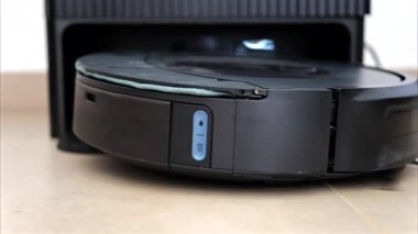Yerde hareket eden ve dönen siyah bir robot elektrikli süpürgeyi kapat.