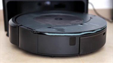 Yerde hareket eden ve dönen siyah bir robot elektrikli süpürgeyi kapat.