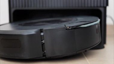 Yerde hareket eden ve dönen siyah bir robot elektrikli süpürgeyi kapat.
