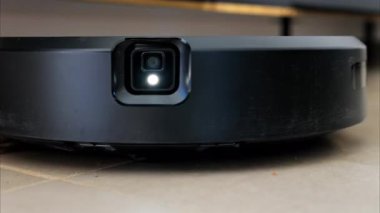 Yerde hareket eden ve dönen siyah bir robot elektrikli süpürgeyi kapat.