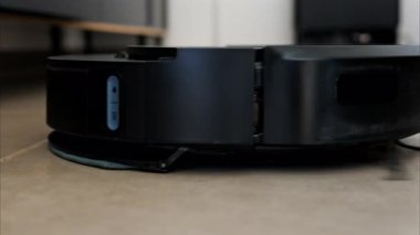 Yerde hareket eden ve dönen siyah bir robot elektrikli süpürgeyi kapat.