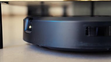 Yerde hareket eden ve dönen siyah bir robot elektrikli süpürgeyi kapat.