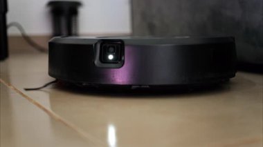 Yerde hareket eden ve dönen siyah bir robot elektrikli süpürgeyi kapat.