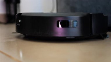 Yerde hareket eden ve dönen siyah bir robot elektrikli süpürgeyi kapat.