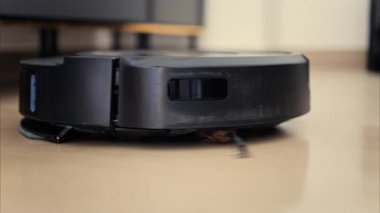 Yerde hareket eden ve dönen siyah bir robot elektrikli süpürgeyi kapat.