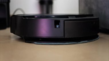Yerde hareket eden ve dönen siyah bir robot elektrikli süpürgeyi kapat.