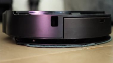 Yerde hareket eden ve dönen siyah bir robot elektrikli süpürgeyi kapat.