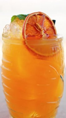 Arka planda bulanık deniz manzaralı bir masanın üzerindeki portakal kokteylini kapat. Dikey