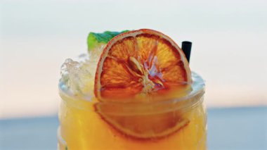 Arka planda bulanık deniz manzaralı bir masanın üzerindeki portakal kokteylini kapat.