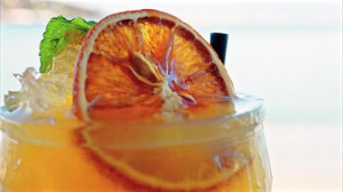 Arka planda bulanık deniz manzaralı bir masanın üzerindeki portakal kokteylini kapat.