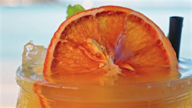 Arka planda bulanık deniz manzaralı bir masanın üzerindeki portakal kokteylini kapat.