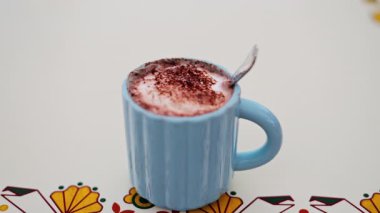 Sıcak çikolatayı beyaz bir masada mavi bardakta yakın.