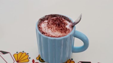 Sıcak çikolatayı beyaz bir masada mavi bardakta yakın.