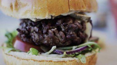 Bir restoranda tabakta bir hamburgeri yakın.