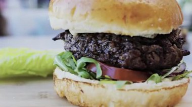 Bir restoranda tabakta bir hamburgeri yakın.