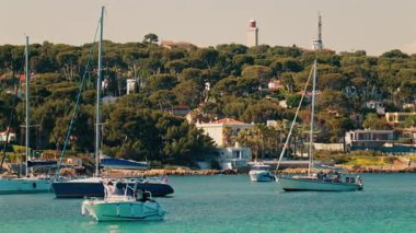 Arka planda yeşilliklerle çevrili villaları olan tekneler denize yanaştı.