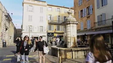 Antibes, Fransa - 27 Nisan 2025: Vauban Limanı girişinin yakınındaki bir çeşmenin yanında yürüyen insanlar