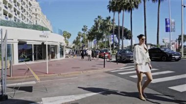 Cannes, Fransa - 29 Nisan 2025: Arka planda Carlton oteli olan caddedeki Hermes mağazasının girişinde yürüyen insanlar