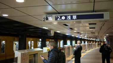 Tokyo, Japonya - 23 Nisan 2025: Asakusa metro istasyonunda maskeli insanlar bekliyor