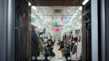 Tokyo, Japonya - 23 Nisan 2025 Metroda oturan ve ayakta duran insanlar