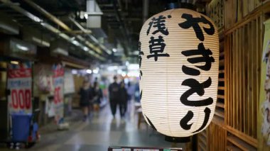 Tokyo, Japonya - 23 Nisan 2025: Bulanık arka planda yürüyen insanlarla yer altı metrosunda beyaz bir kağıt feneri kapatın. Çeviri: Yakitori Asakusa