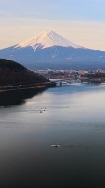 Japonya 'nın Fujikawaguchiko kasabası yakınlarındaki Kawaguchiko Gölü' nde gün batımında hareket eden gemilerin insansız hava aracı görüntüsü.