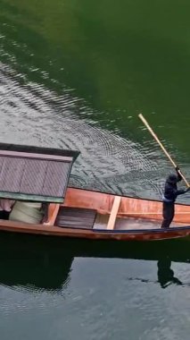 Japonya, Arashiyama 'da gün ışığında hareket halindeki bir teknede uçan bir adamın görüntüsü.
