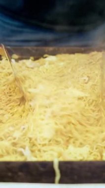 Japonya 'daki bir markette Teppan' da kızarmış erişteleri fırlatmak için metal spatula kullanan bir satıcıyı kapatın. Dikey