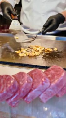 Japonya 'daki Tsukiji Balık Pazarı' nın arka planında aşçı olan Wagyu bifteğinin birden fazla parçasını kapatın. Dikey