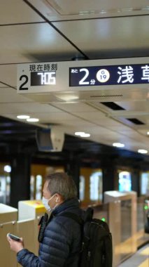 Tokyo, Japonya - 23 Nisan 2025 Asakusa metro istasyonunda maskeli insanlar bekliyor. Dikey