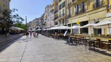 Cannes, Fransa - 23 Ağustos 2024: İnsanlar gün ışığında boş terasların yanında sokakta yürüyor