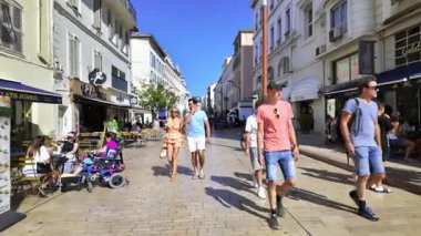 Cannes, Fransa - 23 Ağustos 2024: İnsanlar gün ışığında terasların yanında sokakta yürüyor