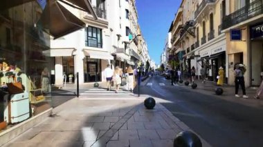 Cannes, Fransa - 23 Ağustos 2024: İnsanlar gün ışığında şehrin sokaklarında mağazaların yakınında yürüyorlar