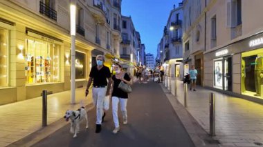 Cannes, Fransa - 24 Ağustos 2024: İnsanlar akşam saatlerinde şehrin sokaklarında mağazaların etrafında yürüyorlar