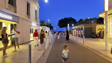 Cannes, Fransa - 24 Ağustos 2024: İnsanlar akşam saatlerinde şehrin sokaklarında mağazaların etrafında yürüyorlar