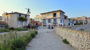 Antibes, Fransa - 29 Ağustos 2024: Arka planda Nicolas Lavarenne 'in bronz heykellerinin yanında yürüyen insanların görüntüsü