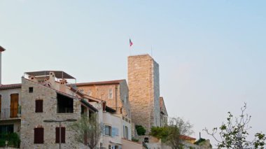 Antibes, Fransa - 29 Ağustos 2024: Picasso Müzesi 'nin tepesinde dalgalanan Fransa bayrağının uzak görüntüsü