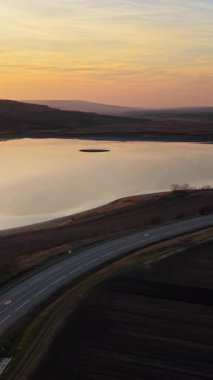 Gün batımında Moldova 'da bir gölün yakınındaki otobanın hava aracı görüntüsü. Dikey