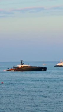Antibes, Fransa 'da gün batımında denizde çok sayıda tekne hareket ediyor. Dikey