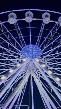 Fransa 'nın Antibes şehrinde akşam vakti sahilde yanan dönme dolap manzarası. Dikey