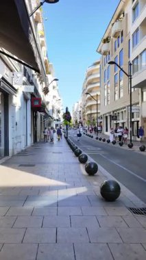 Cannes, Fransa - 23 Ağustos 2024: İnsanlar şehrin sokaklarında gün ışığında mağazaların yakınında yürüyorlar. Dikey