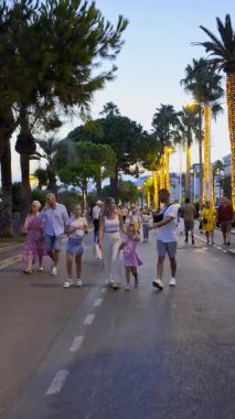 Cannes, Fransa - 24 Ağustos 2024: Akşamları Croisette Bulvarı 'nda yürüyen insanlar. Dikey