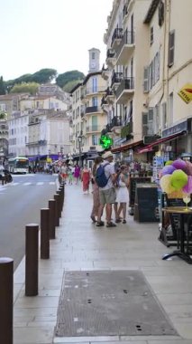Cannes, Fransa - 26 Ağustos 2024: İnsanlar sokakta yürüyor, gün ışığında terasların yanında. Dikey