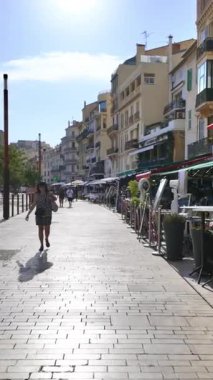 Cannes, Fransa - 26 Ağustos 2024: İnsanlar sokakta yürüyor, gün ışığında terasların yanında. Dikey