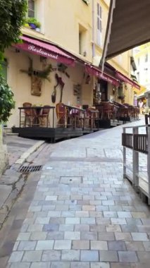 Cannes, Fransa - 26 Ağustos 2024: Sokakta bir yürüyüş, gün ışığında boş terasların yanında. Dikey