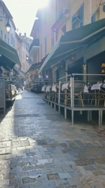 Cannes, Fransa - 26 Ağustos 2024: Sokakta bir yürüyüş, gün ışığında boş terasların yanında. Dikey