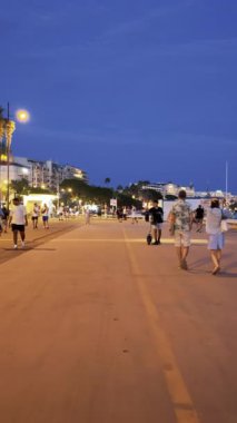 Cannes, Fransa - 26 Ağustos 2024: İnsanlar akşamları şehrin sokaklarında yürüyor. Dikey