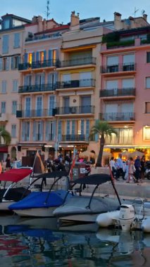 Cannes, Fransa - 26 Ağustos 2024: Akşamları Port de Cannes yakınlarında yürüyen insanlar. Dikey