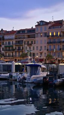 Cannes, Fransa - 26 Ağustos 2024: Gemiler arka planda binalarla birlikte akşamleyin Port de Cannes limanına yanaştı. Dikey